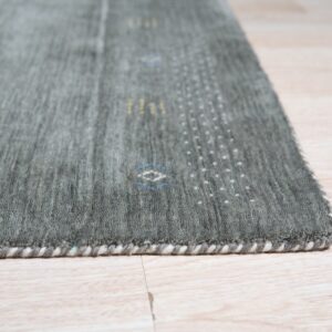 Close view of a gray rug showing subtle blue, yellow, and white geometric patterns on light wood flooring.