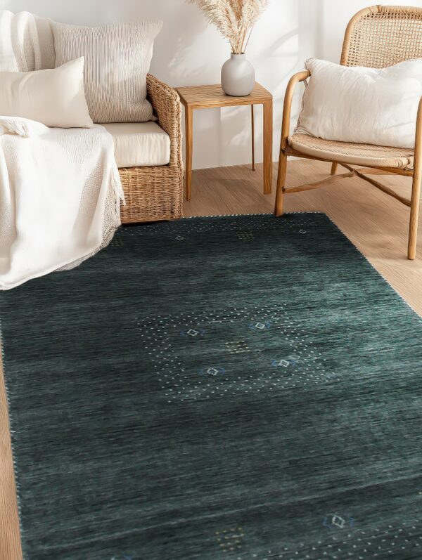 A striated dark teal rug with a dotted pattern lies on wood flooring surrounded by wicker furniture.