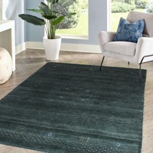 A deep blue-green rug featuring a minimalist dot pattern rests on herringbone wood floor by a window.
