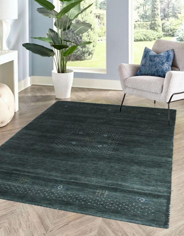 A deep blue-green rug featuring a minimalist dot pattern rests on herringbone wood floor by a window.