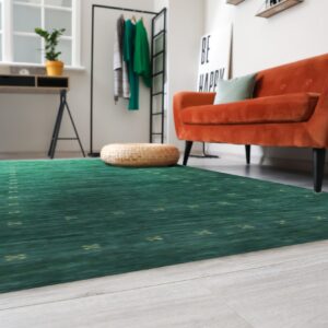 A green rug with repeating yellow motifs covers light flooring in a room with an orange velvet sofa.