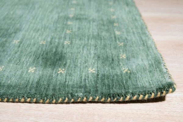 Textured green rug with small yellow cross patterns and contrasting yellow edge binding on light wood.