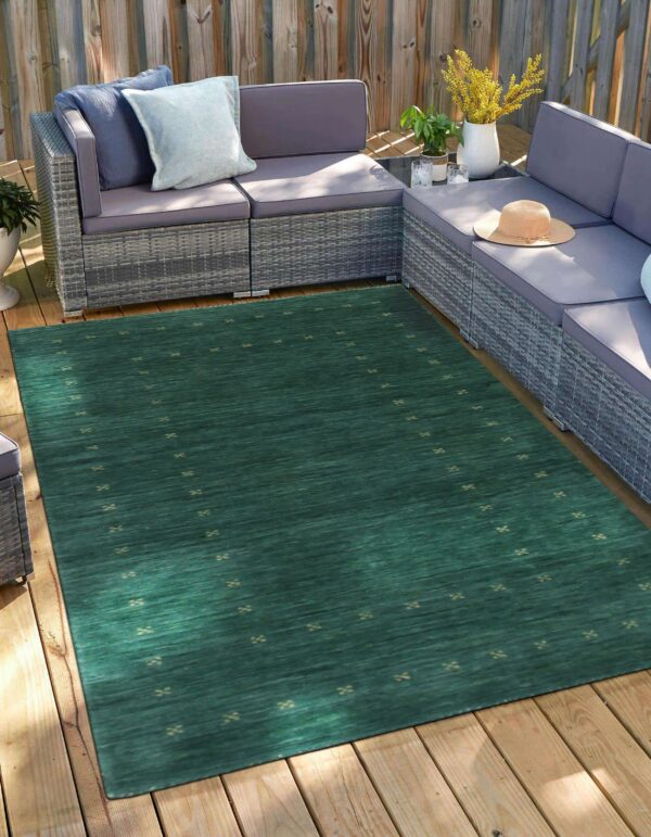 Dark teal rug with small beige repeating motifs sits on a wood deck under gray patio furniture.