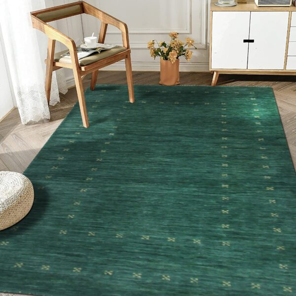 Teal striated rug with small tan geometric patterns placed under a wooden chair on light herringbone flooring.