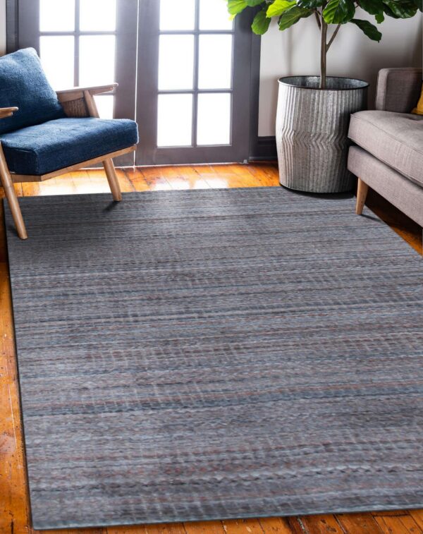 Muted slate-gray striped rug on glossy wood floor near a blue chair and a large indoor plant.