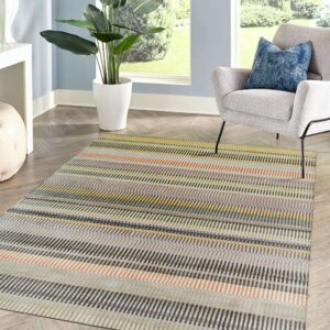 Multi-color dash stripe rug on herringbone flooring next to a grey chair and large window.