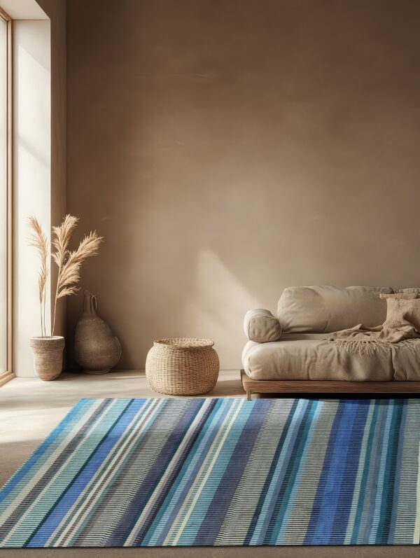 A low-pile blue and gray diagonally striped rug lays on light flooring beside a beige sofa.