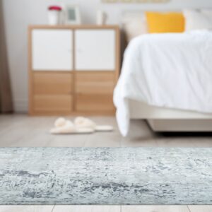 Distressed gray and white abstract rug on a light floor, with a blurred bed in the background.