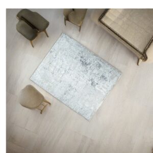 Low-pile silver and gray abstract rug on light wood flooring, surrounded by vintage upholstered furniture.