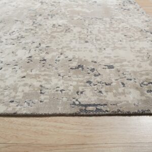 A beige and gray abstract rug with a textured high-low pile rests on light wooden floorboards.