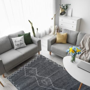 A charcoal gray geometric rug with white patterns anchors two light gray couches on light wood flooring.