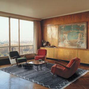 Dark gray textured rug with a zigzag border under three armchairs on a wood paneled wall backdrop.