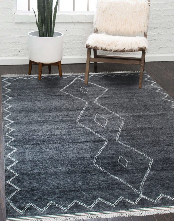 Charcoal rug with white zig-zag and diamond patterns placed under a white shaggy wooden chair.