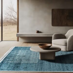 Teal blue rug with white linear patterns anchors a gray coffee table and textured armchair on wood floors.
