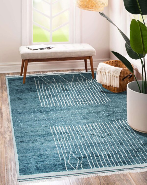 Teal blue rug with abstract white vertical stripes and speckles on wood floors near a window bench.