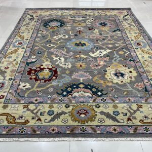 Multicolored floral pattern rug with a gray field and pale border displayed on a white tile floor.