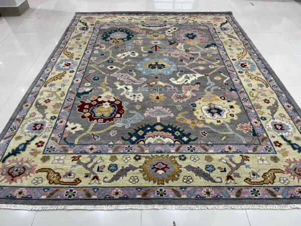 Multicolored floral pattern rug with a gray field and pale border displayed on a white tile floor.