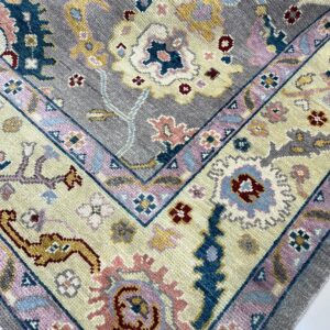 Thick pile rug with a traditional floral pattern in gray, cream, blue, and pink hues on a white floor.