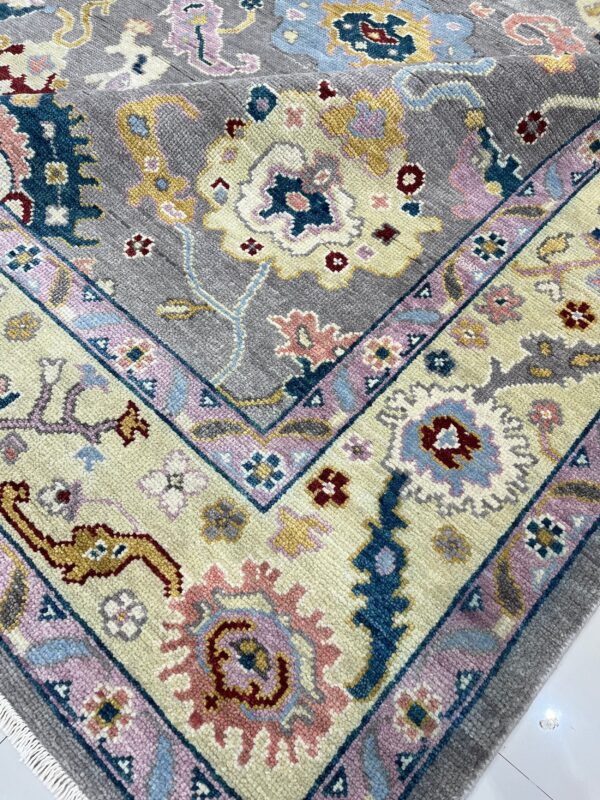 Thick pile rug with a traditional floral pattern in gray, cream, blue, and pink hues on a white floor.