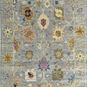Low-pile blue rug with an ornate traditional pattern of gold, yellow, purple, and green floral motifs.
