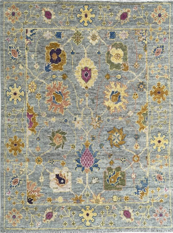 Low-pile blue rug with an ornate traditional pattern of gold, yellow, purple, and green floral motifs.