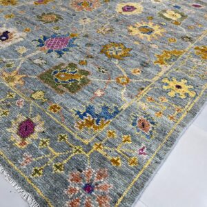 Textured gray-blue rug featuring a vibrant multicolor traditional floral pattern on glossy white tiles.