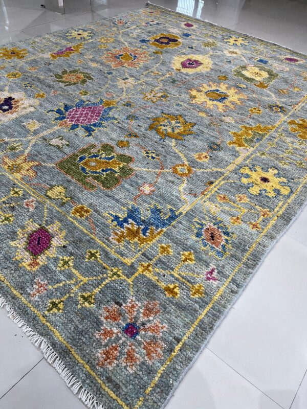 Textured gray-blue rug featuring a vibrant multicolor traditional floral pattern on glossy white tiles.