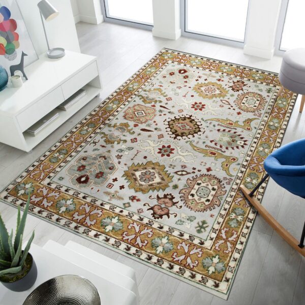 Light gray traditional area rug featuring gold, red, and green borders on light wood flooring.