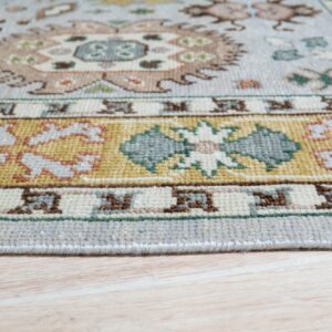 Ornate light blue rug with gold, cream, and teal borders rests on pale wooden floorboards.