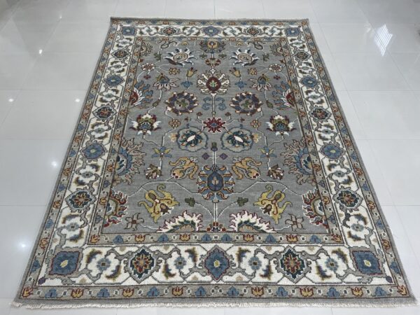 Traditional gray rug with a multicolored floral pattern and ivory borders rests on white tile flooring.