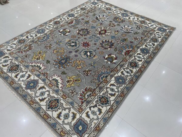 Gray rug with colorful floral and medallion patterns, featuring a wide ivory border on glossy white tile.