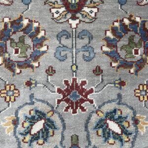 Close-up of a gray rug featuring intricate traditional motifs in red, blue, yellow, green, and cream.