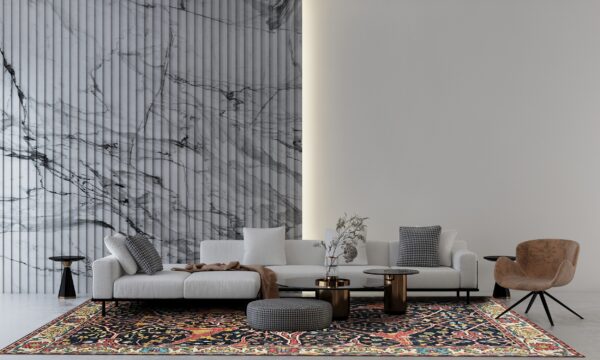 A dark navy traditional rug with red and yellow accents anchors a modern living room with a white sofa and marble wall.