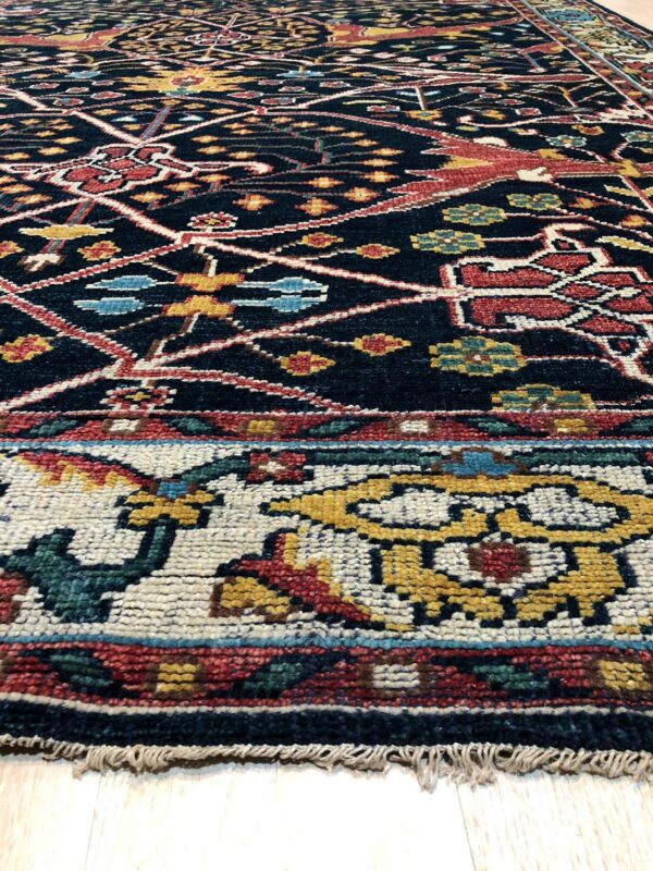 Detailed dark rug with colorful geometric patterns in red, gold, and blue, visible on light flooring.