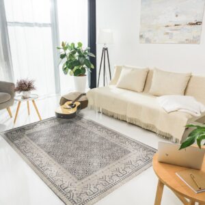 Geometric gray and beige patterned area rug grounding a bright living room with a sofa and gray armchair.