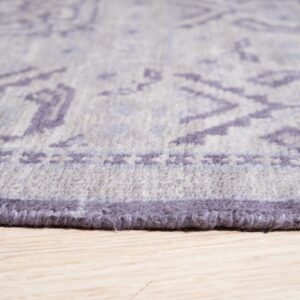 Plush gray and purple rug edge with tribal pattern details shown on light wood planks.
