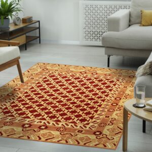 Traditional rug in red and golden yellow with geometric patterns lies between a beige sofa and armchair.
