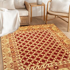 Red and gold geometric rug on wood floors between woven rattan sofa and chair.