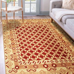 Red and gold geometric rug with multiple borders near a gray sofa and wooden chair on wood plank flooring.