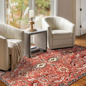 A rust traditional patterned rug grounds a sitting area with two white accent chairs on hardwood floors.