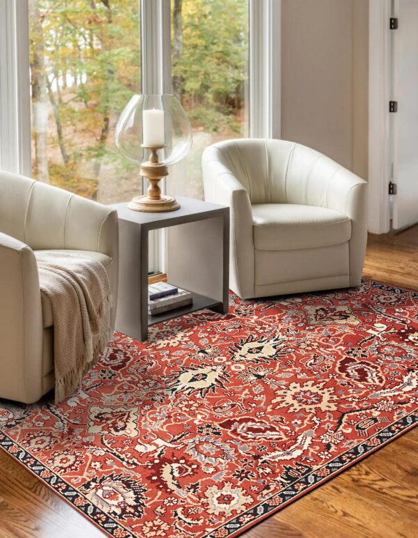 A rust traditional patterned rug grounds a sitting area with two white accent chairs on hardwood floors.