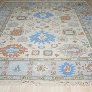 Traditional ivory rug with blue, gray, and orange medallion patterns displayed on light wood flooring.