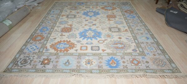 Traditional ivory rug with blue, gray, and orange medallion patterns displayed on light wood flooring.