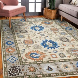 Cream rug with blue, orange, and gray tribal medallions anchors a room with a pink chair and wood floor.