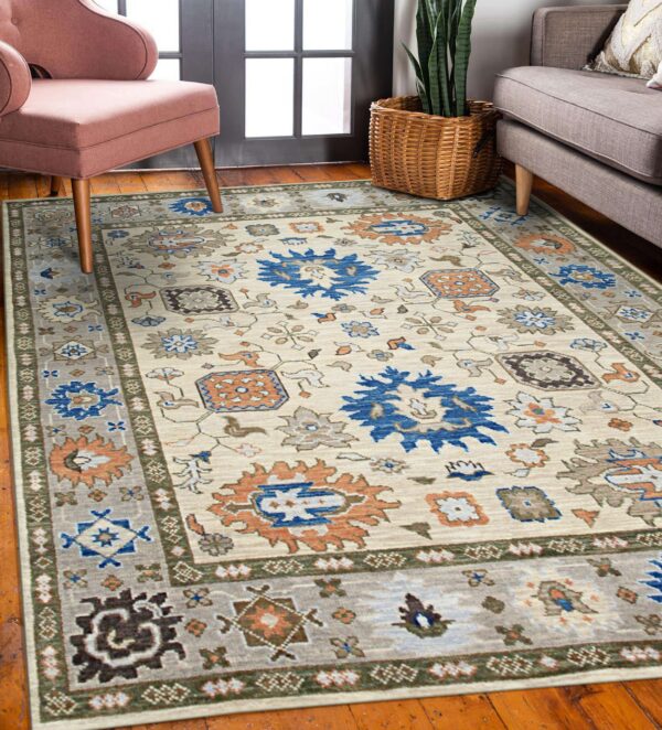 Cream rug with blue, orange, and gray tribal medallions anchors a room with a pink chair and wood floor.