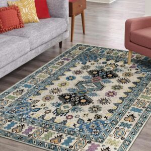 Low pile rug featuring blue and multicolor geometric patterns on gray wood floors in a bright room.