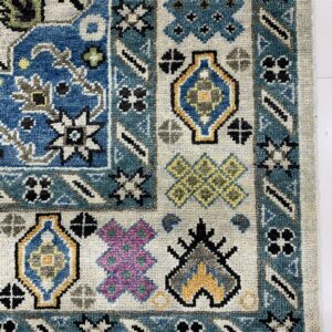 Close-up detail of a textured rug with geometric motifs in blue, teal, yellow, magenta, and gray.