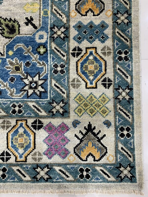 Close-up detail of a textured rug with geometric motifs in blue, teal, yellow, magenta, and gray.