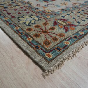 High-pile gray rug with red, blue, and orange geometric border lying on light wood flooring.