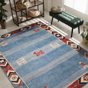 Light blue rug featuring abrash stripes, primitive figures, and a red geometric border in a sunlit room.
